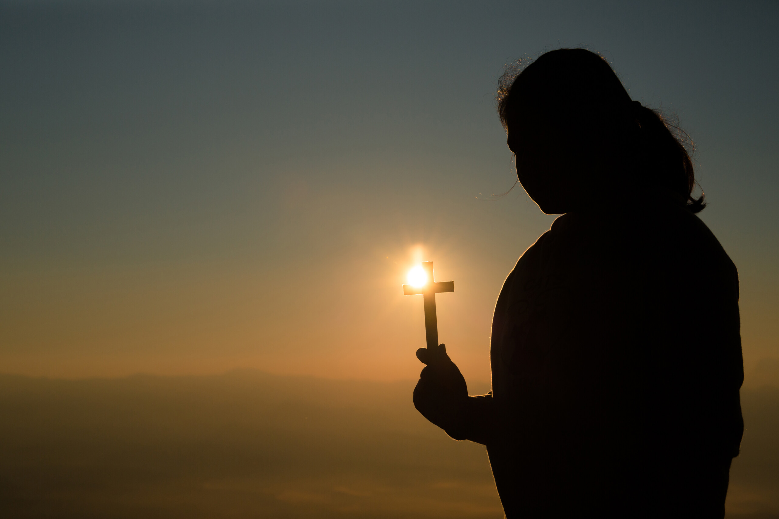 Teenage girl holding cross with praying. Peace, hope, dreams con